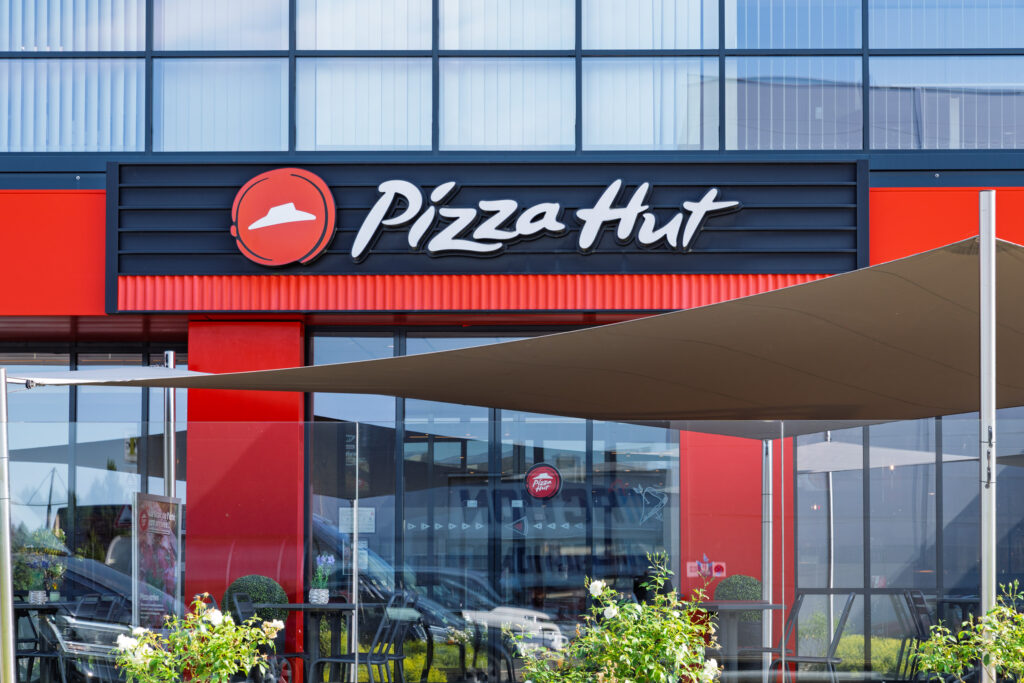 Facade and sign of the Pizza Hut Wemperhardt restaurant with shaded terrace, opposite the Massen Shopping Center